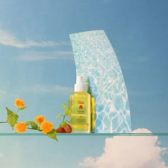 Huile intime bio au chanvre et macadamia, hydratation naturelle, fond bleu apaisant, fleurs orangées.