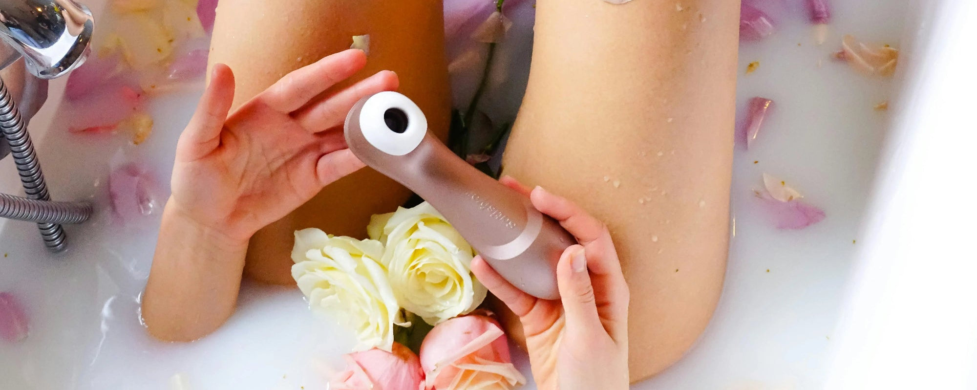 Une femme se détend dans une baignoire remplie de fleurs, avec un vibromasseur à ses côtés.