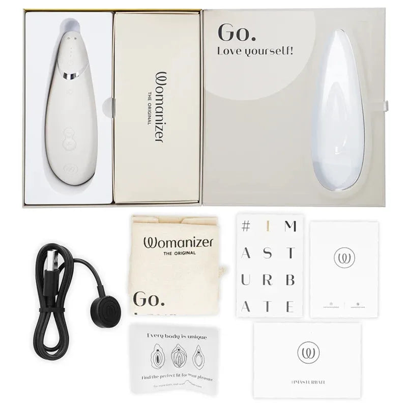 Stimulateur clitoridien Womanizer blanc, compact et rechargeable, avec accessoires tendance.