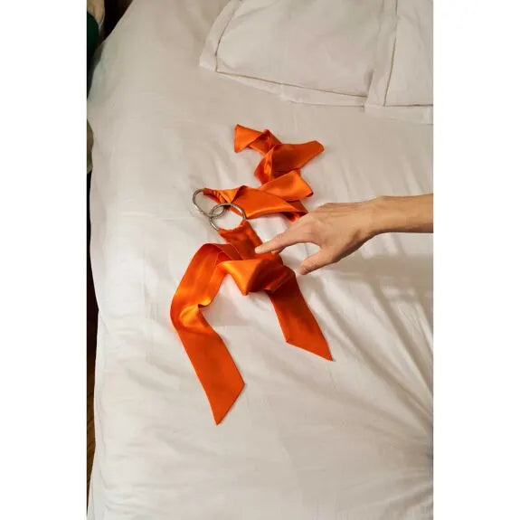 Rubans en satin orange avec menottes pour jeu de bondage élégant.