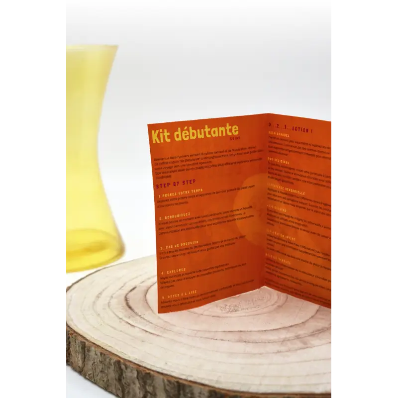 Un vase jaune avec une brochure orange, symbolisant l'exploration et le plaisir d'un kit intime pour couples.